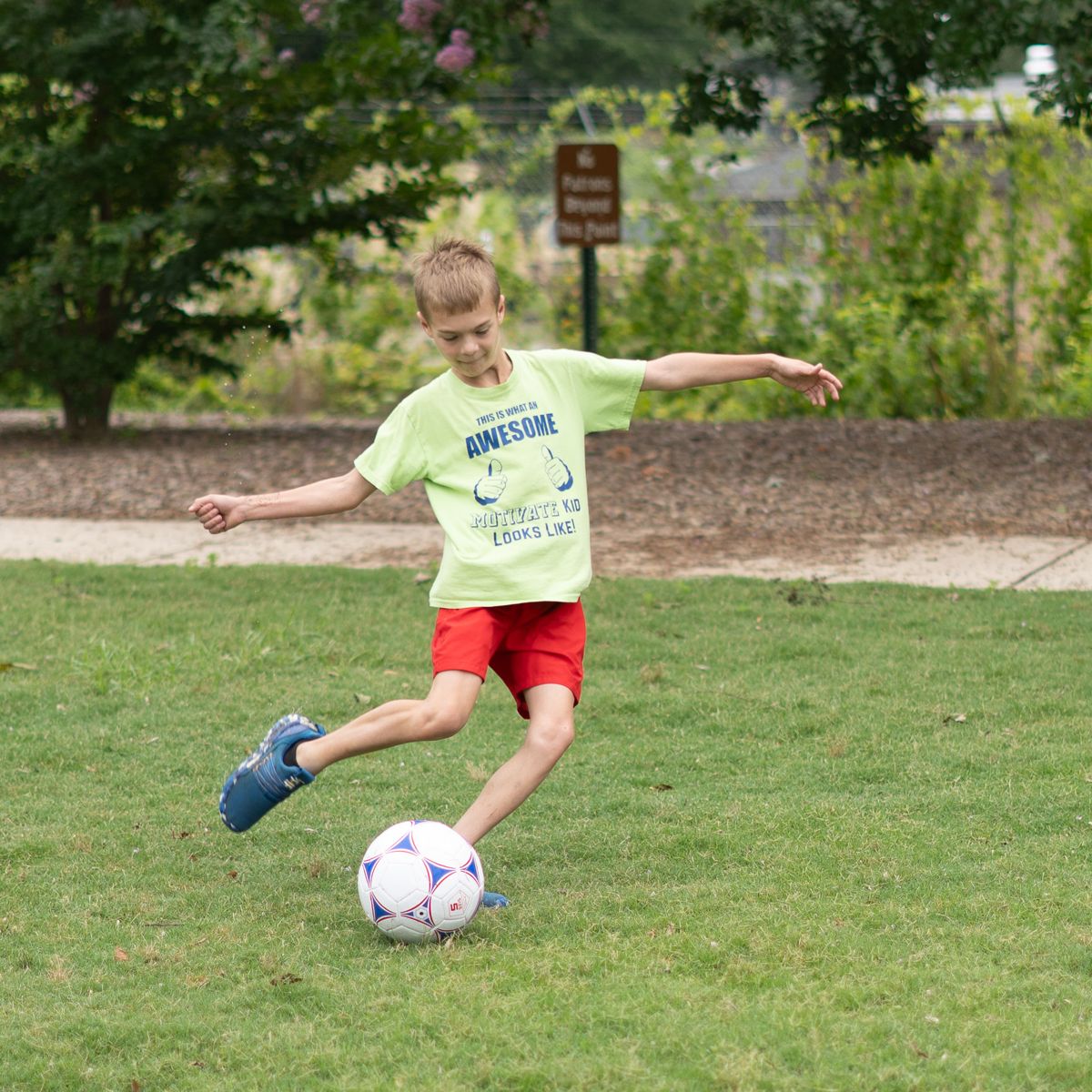 A Motivate student kicking a soccer ball on the grass