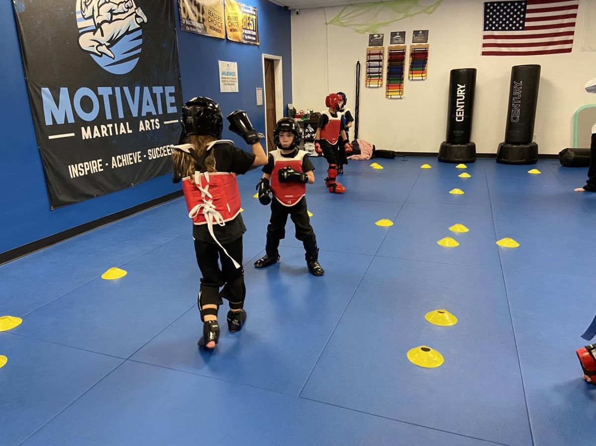 Young students in helmets and chest guards sparring on the mat